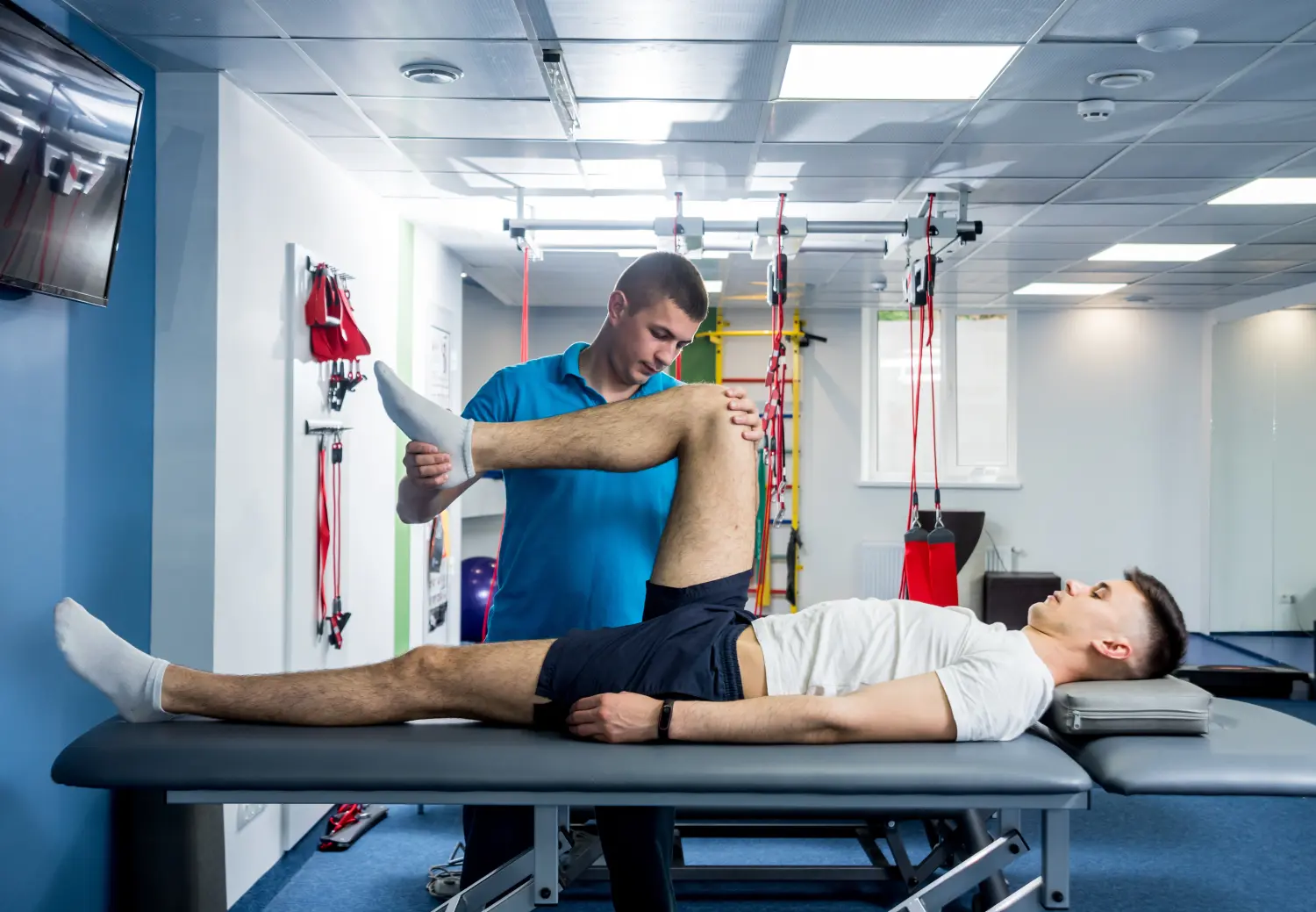 Rehabilitationstherapie. Physiotherapeutin bei der Arbeit mit einem jungen männlichen Patienten im Rehabilitationszentrum 